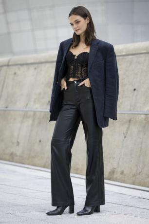 Una donna indossa pantaloni di pelle nera, un blazer oversize e un bustier di pizzo, un outfit pantalone di pelle da provare per il 2023