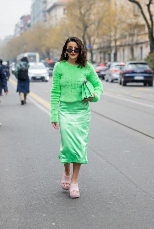 En kvinna bär en ljusgrön midikjol och topp