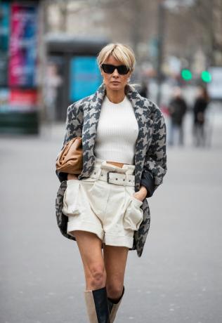 Femme portant un short blanc avec un tee-shirt blanc et une veste pied-de-poule.