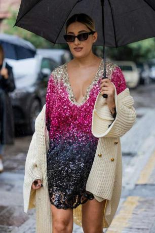 Una donna indossa un cardigan beige con un mini abito sfumato di paillettes, un'idea outfit cardigan 2023 per donna.