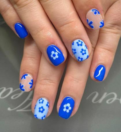 Une femme portant un dessin d'ongles monochromatique en forme de fleur de blues