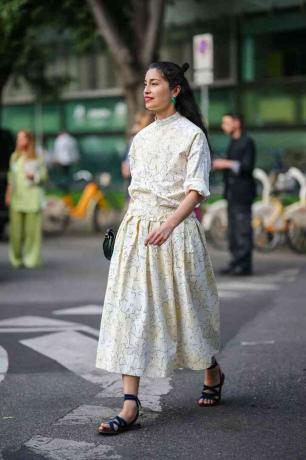 La mujer viste la parte superior e inferior floral amarilla con sandalias azules