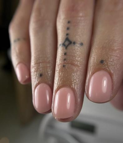 Uma mulher usando um design de unhas simples com um tom rosa leitoso