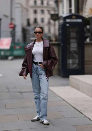 Mulher vestindo jaqueta de couro grande com blusa branca e jeans reto