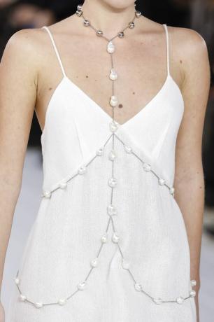 Een model draagt ​​een body chain van fijne sieraden, een van de grootste sieradentrends van de zomer van 2023.