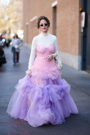 Una mujer lleva un jersey de cuello alto blanco debajo de un vestido de tul, una idea de outfit de cuello alto para mujer de 2023. 