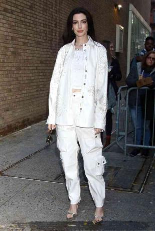 Anne Hathaway i hvid jakke og matchende cargobukser poserer New York City nov. 27