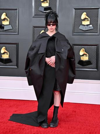 Billie Eilish con chaqueta negra oversize y vestido con botas