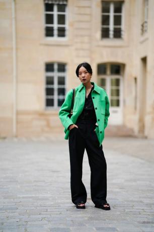 Mujer con una chaqueta verde brillante sobre un conjunto negro.