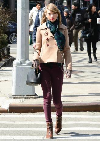 Тейлор Свифт в светло-коричневом пальто и зеленом клетчатом шарфе.