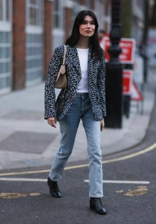 Uma mulher usa um blazer estampado sobre jeans, uma ideia de look com blazer para as mulheres experimentarem em 2023.
