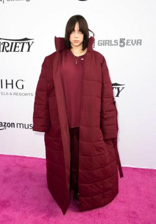 Billie Eilish lielizmēra bordo krāsas mētelī, topā un biksēs