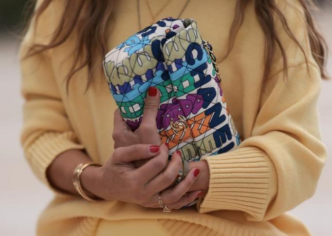 Una mujer con uñas rojas sosteniendo un bolso Chanel.