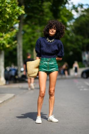 Una mujer viste un conjunto de pantalones cortos y sandalias con pantalones cortos de cuero y un suéter