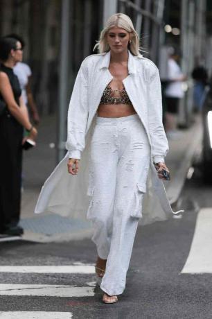 Kvinnan bär kavaj och byxor med vita paljetter plus en färgglad bralette
