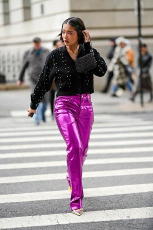 Una donna indossa pantaloni di pelle metallizzata rosa e un maglione nero, un outfit con pantaloni di pelle da provare per il 2023