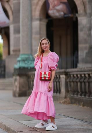 Une femme montre comment associer une robe de sieste avec un sac à rayures et des baskets tendance