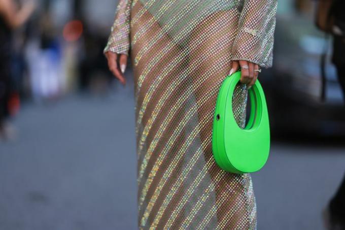 Naine kannab läbipaistvaid värvilisi riideid ja hoiab käes rohelist kotti, klassikalist Sõnni värvi.