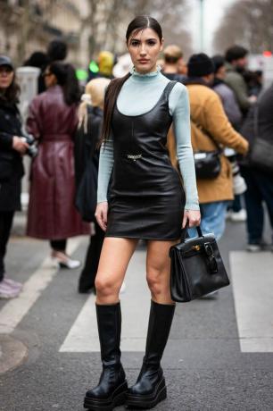 Patricia Manfield usa uma gola rulê azul clara sob um mini vestido de couro preto, uma ideia de roupa de gola alta para 2023 para mulheres. 