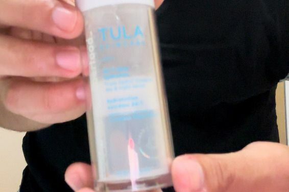 Ένα άτομο κρατά ένα μπουκάλι TULA 24-7 Ultra Hydration Triple-HydraTM Complex Day & Night Serum