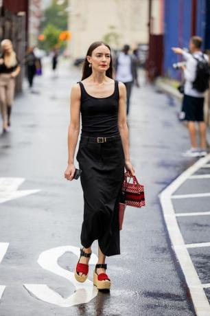 Žena v dlouhých černých šatech jdoucí po ulici