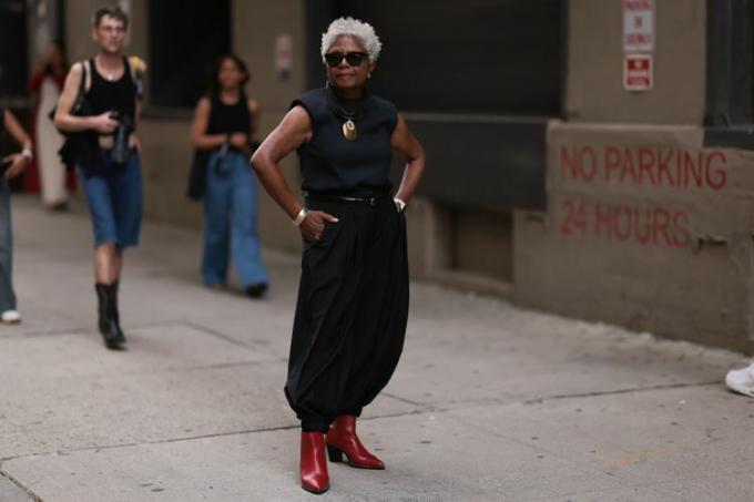 Žena v černém tílku, černých kalhotách a červených kožených botách