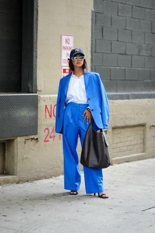 एक महिला एक बड़े आकार का नीला सूट पहनती है