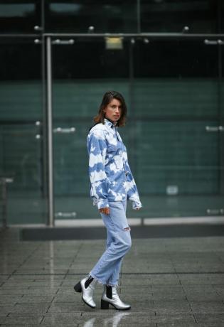 Жінка в джинсах і джинсовій куртці кислотного прання зі сріблястими черевиками Челсі. 