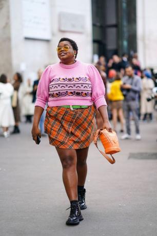 Žena nosi ružičasti džemper i kariranu suknju, ideja za kariranu suknju koju će žene isprobati u jesen 2023.
