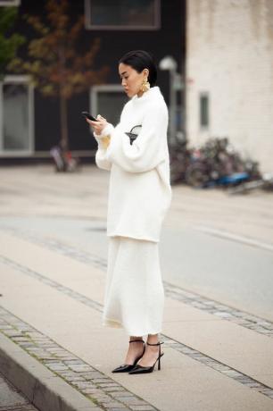 Жена носи бял пуловер и пола