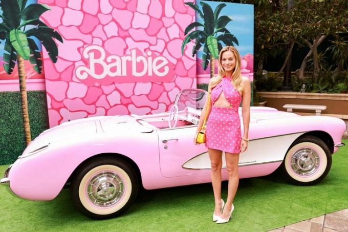 მარგო რობი პოზირებს Barbiecore-ის ჩაცმულობით Barbie-ს ოცნების მანქანის გვერდით, რომელსაც Barbie-ის ტანსაცმელი აცვია Barbie Press-ის ტურზე.