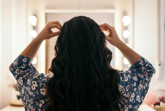Zadní pohled na nerozeznatelné ženské dlouhé vlnité vlasy v kadeřnickém a kosmetickém studiu