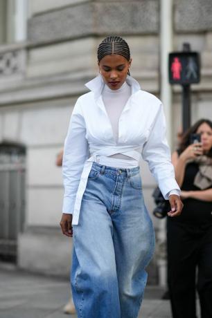 Tina Kunakey trägt einen weißen Rollkragenpullover und Jeans mit weitem Bein, eine Rollkragen-Outfit-Idee für Frauen im Jahr 2023. 