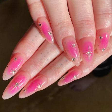 En kvinde iført en pink manicure med et stjerneformet negledesign i krom