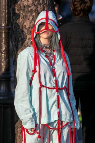Billie Eilish su šviesiai mėlynu kombinezonu su raudonos virvės detalėmis