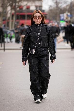 Žena v černé kombinéze Chanel s černou kabelkou Chanel