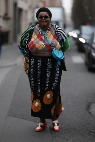 Une femme porte un gilet pull à losanges et une jupe en tricot